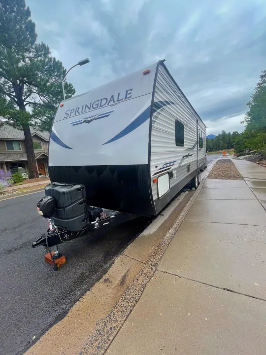Springdale travel trailer, a great option for your next RV rental, parked on a wet street on a cloudy day.. Keystone RV Springdale 2020