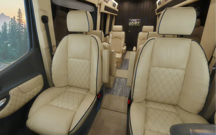 Luxury RV rental interior: cream quilted captain's chairs, TV, and scenic mountain views from a spacious, comfortable cabin.. Ultimate Toys Ultimate Coach 2023