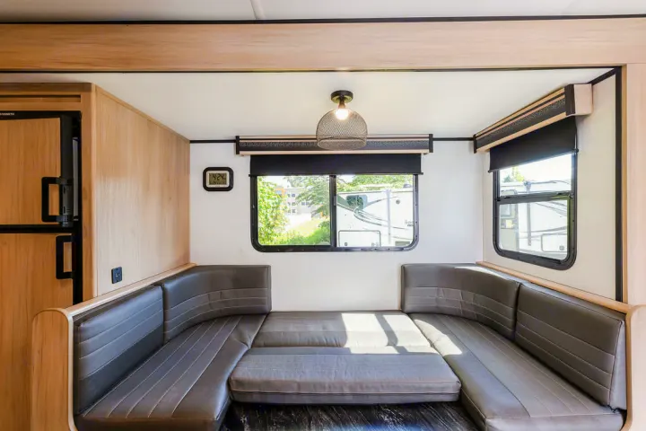 An RV rental interior showing a comfortable U-shaped dinette area with cushions laid flat to form a bed.. North Trail 24bhs 2021