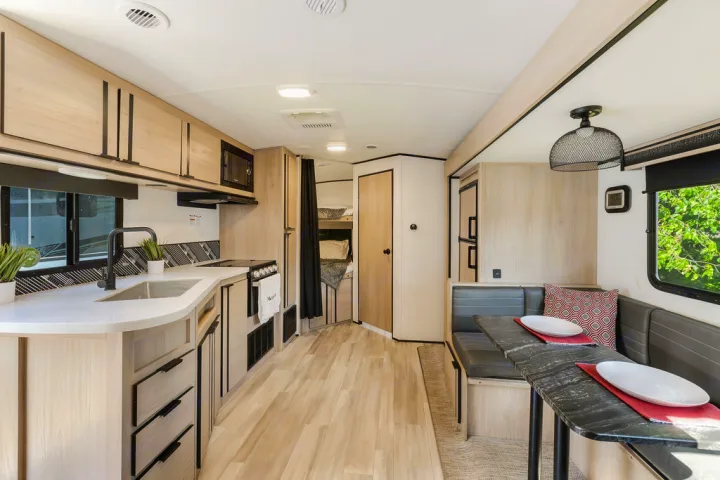 This RV rental offers a bright, modern interior with a well-equipped kitchen, dining dinette, and bunk beds.. North Trail 24bhs 2021