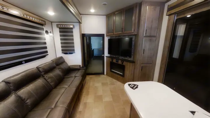 Comfortable RV rental living space featuring a leather sofa, entertainment center with TV & fireplace, and ample cabinets.. Forest River Vengeance Rogue Armored Toy Hauler 2021