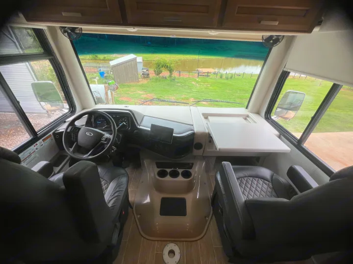 Spacious RV rental cockpit with a serene view of a pond. Ready for your next motorhome adventure!. Thor Outlaw 2022