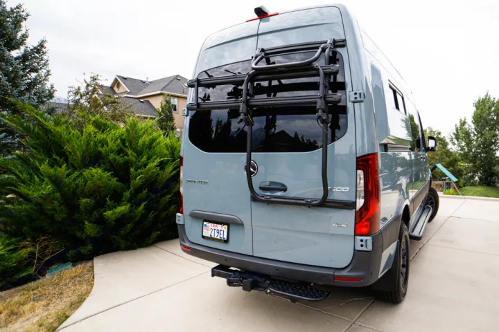 Rear view of a grey Mercedes Sprinter 4x4 RV rental, equipped with a bike rack & step.. Mercedes Sprinter 2021