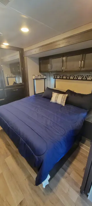 Cozy RV rental bedroom with queen bed, overhead storage, and mirrored wardrobe.. Jayco Greyhawk 2021