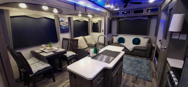 Experience luxury in this RV rental's inviting living and dining areas, plus a modern kitchen with blue accent lighting.. Crossroads RV Volante HP 2022
