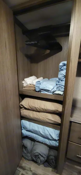 RV rental's organized closet features a hanging rod, shelves, and neatly folded linens and blankets.. Crossroads RV Volante HP 2022