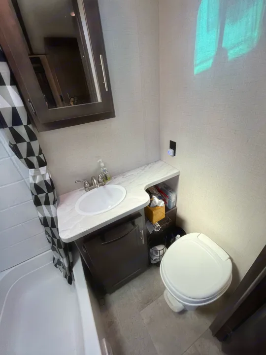 This RV rental bathroom features a compact layout with a sink, toilet, shower, and small storage.. Crossroads RV Sunset Trail Super Lite 2018