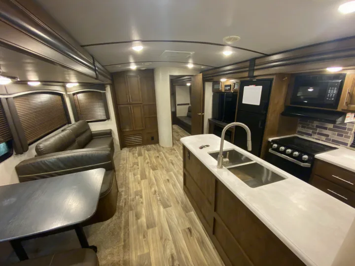 Spacious RV rental interior featuring a full kitchen, living area with sofa, and dining booth. Perfect for comfortable travel.. Keystone Cougar Half-Ton 2021