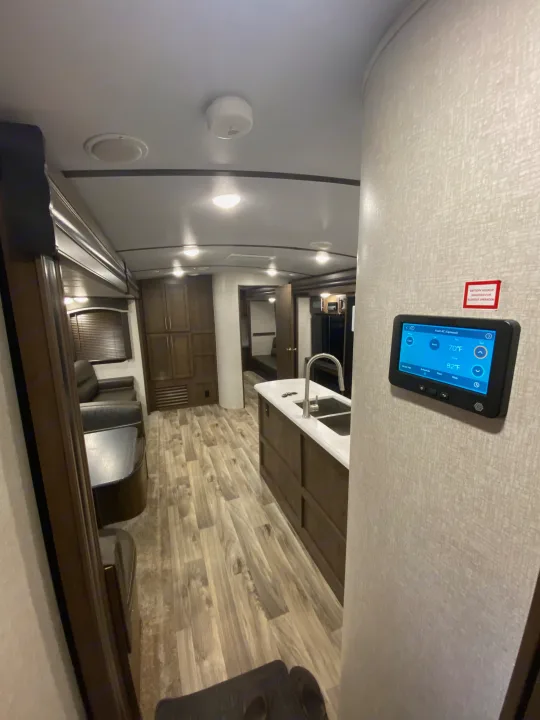 Step inside this modern RV rental, featuring a kitchen island, wood-look flooring, and a digital system control panel.. Keystone Cougar Half-Ton 2021