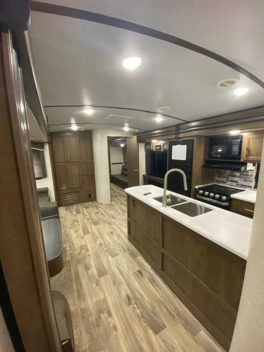 Spacious RV rental interior featuring a modern kitchen with island sink, stove, and comfortable living area for your travels.. Keystone Cougar Half-Ton 2021