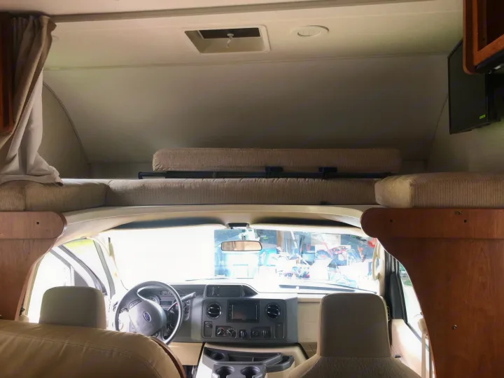 Inside this RV rental: The driver's cockpit view with dashboard and steering wheel, plus the comfortable overhead bunk.. Winnebago Minnie Winnie 2016