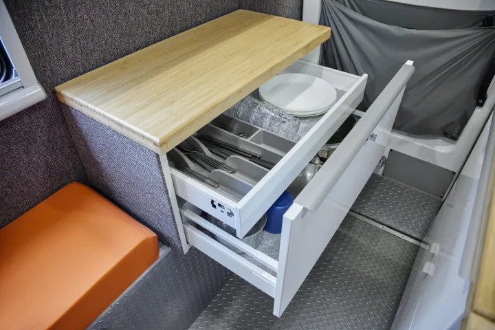 RV rental kitchen drawers open, revealing organized plates, cups, and utensils. Compact and efficient storage.. Chevrolet silverado 2500 2022