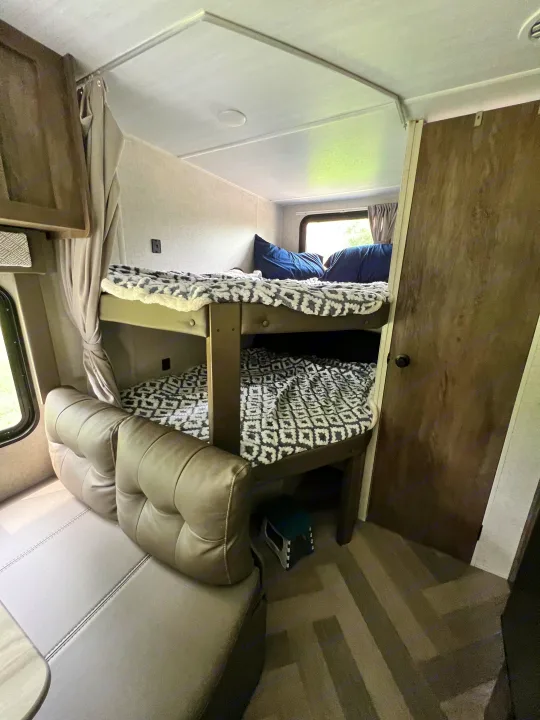 Cozy RV rental interior with bunk beds, soft blankets, and comfortable dinette seating for family travel.. Forest River Salem Cruise Lite 2021