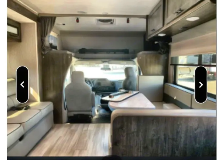 RV rental interior: A light, modern living space with dinette, sofa, and front cabin. Wood-look flooring extends throughout.. Coachmen Leprechaun 2022