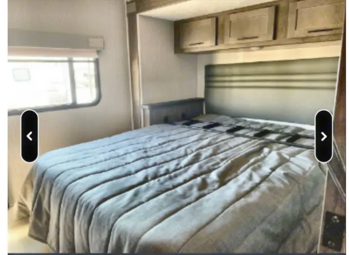 Cozy RV rental bedroom with a comfy bed, overhead cabinets, and a window for natural light. Ideal for your next adventure.. Coachmen Leprechaun 2022