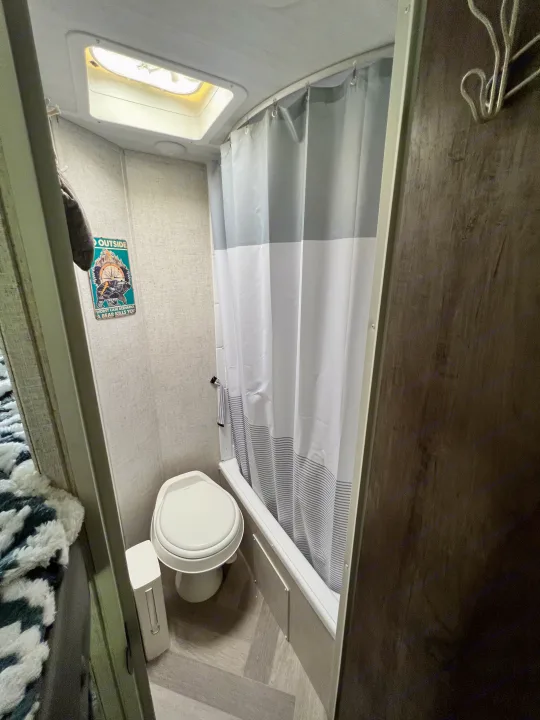 RV rental bathroom features a toilet, shower, skylight, and a fun bear sign on the wall, ideal for travel.. Forest River Salem Cruise Lite 2021