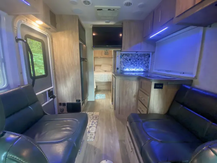 Spacious RV rental interior with black leather seating, a modern kitchen, and bedroom amenities for comfortable travel.. Forest River Sunseeker 2017