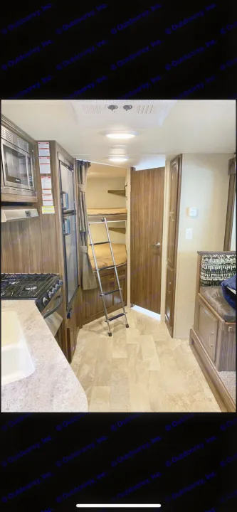 Spacious RV rental interior featuring a full kitchen, comfy bunk beds with ladder, and cozy dinette seating, perfect for family adventures.. Coachmen Apex 2018