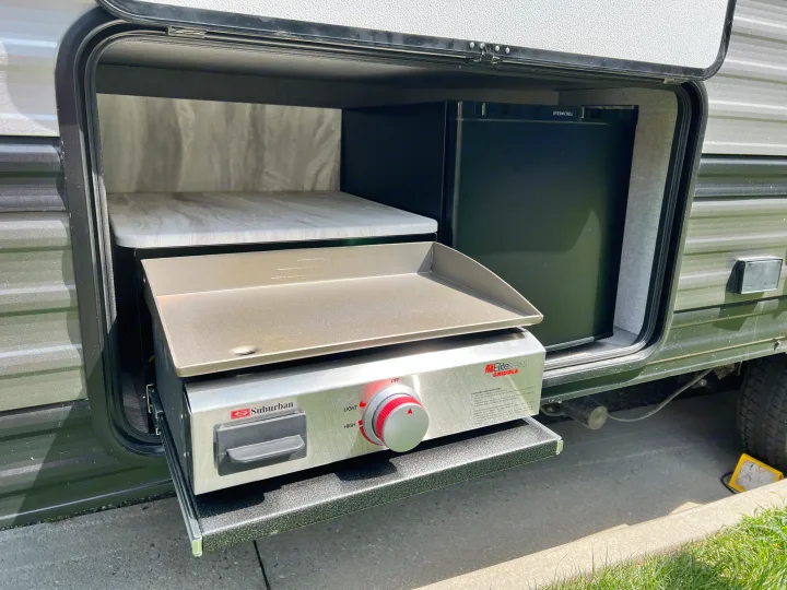 RV rental outdoor kitchen featuring a pull-out griddle and compact fridge, perfect for on-the-go cooking.. Forest River Salem Cruise Lite 2021