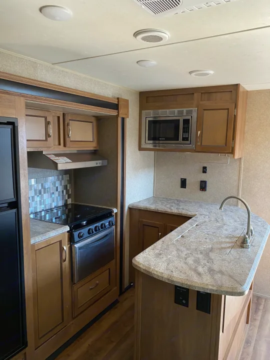 Spacious RV rental kitchen featuring a refrigerator, stove, microwave, sink, and ample cabinets.. Coachmen Catalina 2019