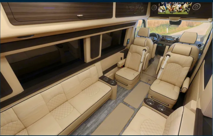 Spacious RV rental interior: cream leather sofa & captain chairs, diamond-stitched, with an entertainment screen.. Ultimate Toys Ultimate RV 2023