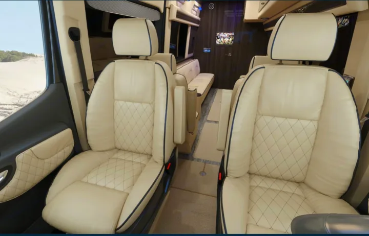 Premium RV rental interior showing cream quilted leather captain's chairs and spacious cabin with a TV.. Ultimate Toys Ultimate RV 2023