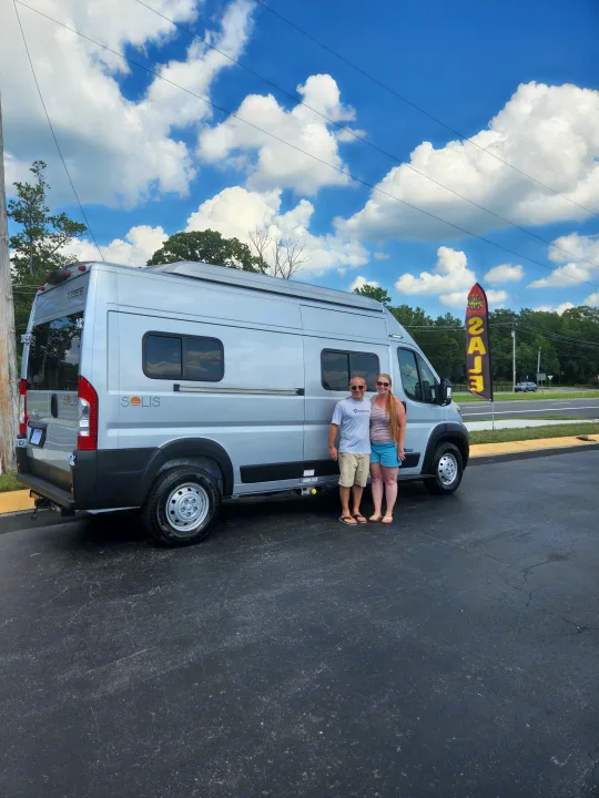 Celebrating a new rv rental! A smiling couple poses with their silver Winnebago Solis camper van.. Winnebago Solis 2022