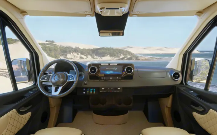 Modern Mercedes-Benz RV rental interior, showing its detailed cockpit with screen and steering wheel, overlooking a beach.. Ultimate Toys Ultimate RV 2023
