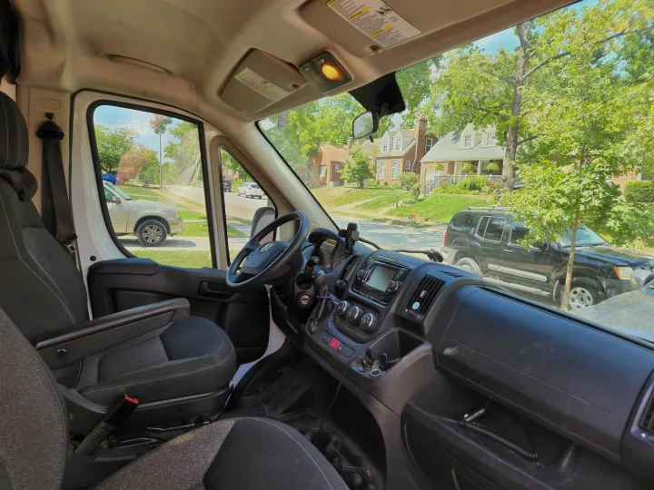 Driver's seat view inside an **rv rental**, showing the dashboard, steering wheel, and a sunny residential street outside.. Dodge 1500 2014