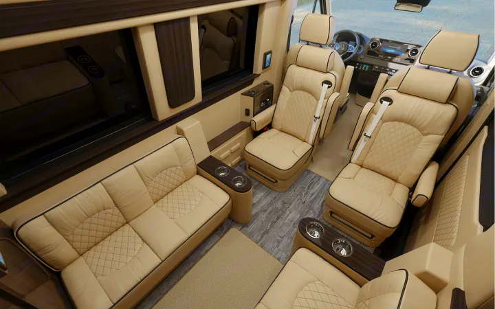 Luxurious RV rental interior features cream quilted leather seating, including a sofa and captain's chairs, with dark wood accents.. Ultimate Toys Ultimate Cruiser 2022