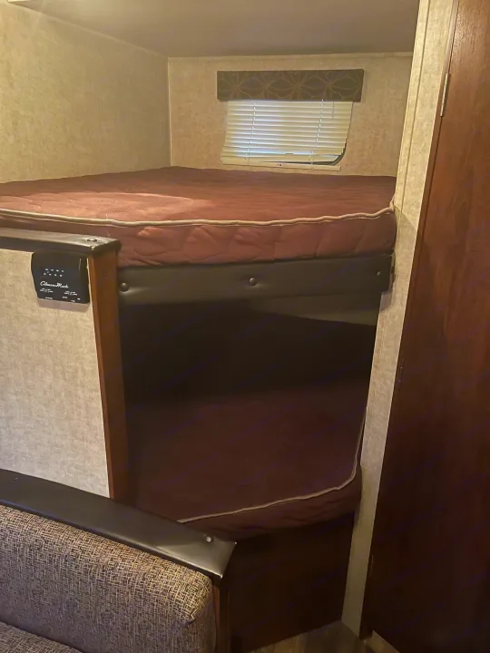 RV rental bunk beds: a cozy interior sleeping area with top and bottom bunks, window, and climate control panel.. Keystone Hideout 2016