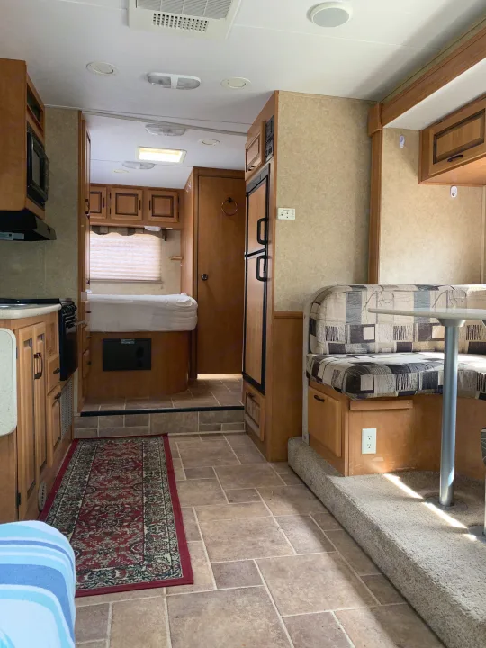 A well-appointed RV rental interior: kitchen, raised bed area, and dinette booth with patterned cushions and easy-clean floors.. Forester Forester Motorhome 2010