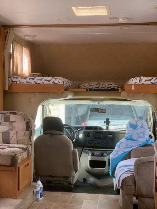 Inside an RV rental, viewing the cockpit from the rear. Features overhead bunks, driver & passenger seats, and a dinette.. Forester Forester Motorhome 2010