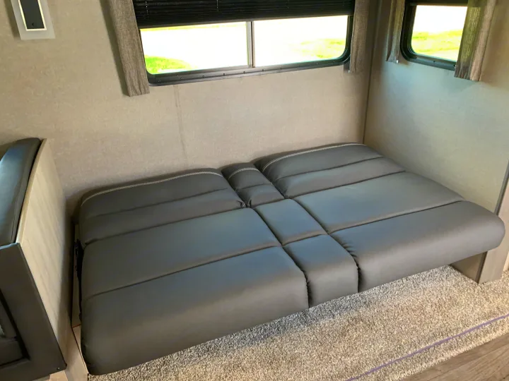 Inside this RV rental, a gray modular seating area converts to a bed, set against walls with large windows.. Forest River Coachmen Catalina Legacy 2022