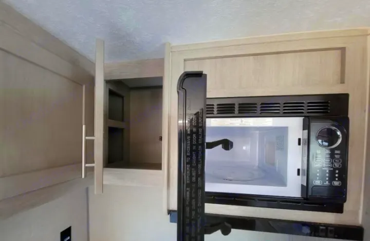 RV rental kitchen: Microwave and open overhead cabinets offer compact storage in this RV interior.. Forest River Coachmen Catalina Legacy 2022