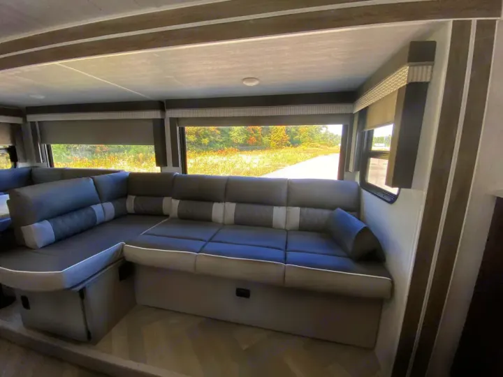 Explore this RV rental's spacious interior with an L-shaped sofa, large windows, and modern design.. Forest River Wildwood X-Lite 2022