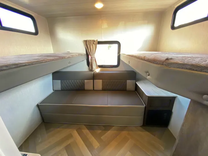 This RV rental bunk room features a convertible sofa bed and two upper bunks for versatile family sleeping.. Forest River Wildwood X-Lite 2022
