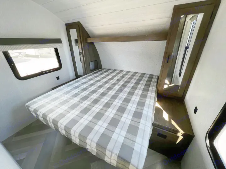 RV rental interior: A modern bedroom with a plaid bed, window, and mirrored cabinet. Comfortable space for travel.. Forest River Wildwood X-Lite 2022