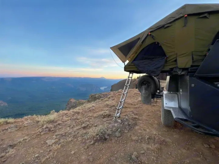 RV rental adventure: a rooftop tent on a trailer offers epic cliffside views over a valley at sunset.. Vorsheer Vorsheer Trailer 2022