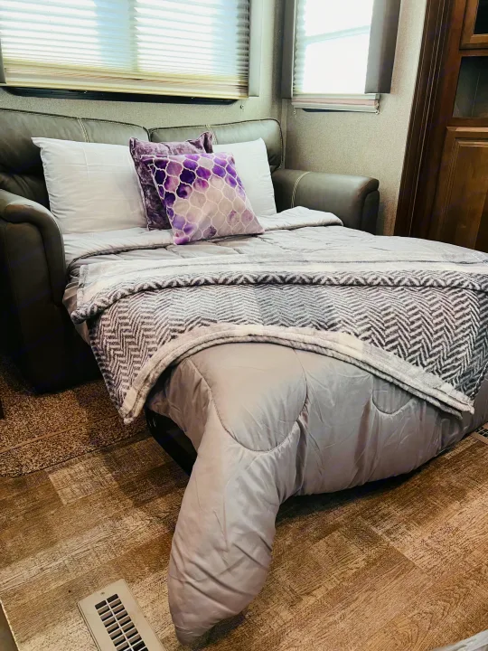 RV rental interior with a comfortable pull-out sofa bed, grey bedding, and decorative purple pillows.. Forest River Rockwood Ultra Lite 2020