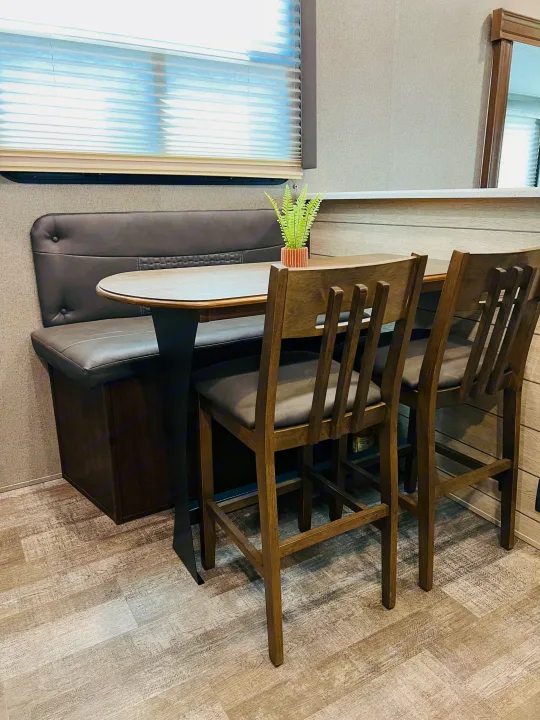 Modern RV rental dinette with cozy bench seating, wooden table, and stools. Perfect for dining & relaxing.. Forest River Rockwood Ultra Lite 2020