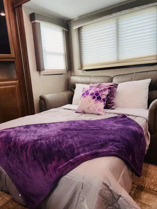 Cozy RV rental interior with a sofa converted into a bed, featuring a vibrant purple blanket and decorative pillows.. Forest River Rockwood Ultra Lite 2020