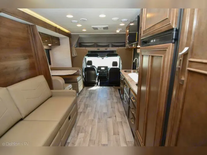 Spacious RV interior, ideal for an RV rental adventure, featuring a comfy sofa, dining area, kitchen, and driver's cabin.. Jayco 24M 2022