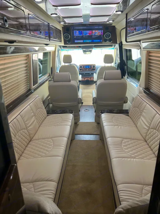 Plush RV rental interior: cream leather sofas, captain chairs, and an entertainment screen. Ideal for luxurious journeys.. Ultimate Toys Other 2022