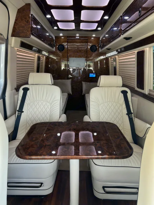 Luxury RV rental interior with plush white seating, wood table & elegant paneling.. Ultimate Toys Other 2022