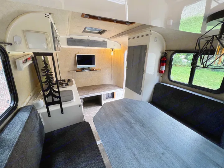 Inside a compact RV rental: modern interior with grey dinette, kitchen, TV, and comfy seating.. Scamp Scamp Trailer 2007