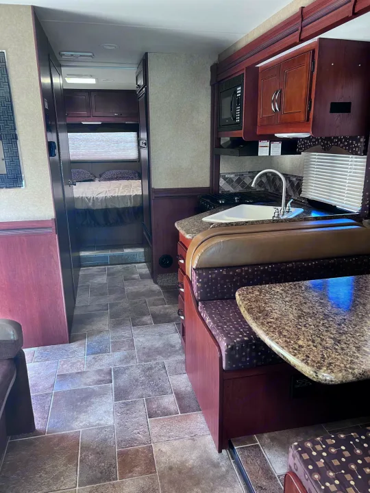 Inside this spacious RV rental: full kitchen, dining booth, and private bedroom.. Thor Freedom Elite 2015