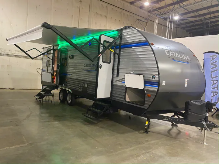 A stylish grey Catalina travel trailer with extended green LED awning and open steps, ideal for your RV rental.. Forest River Coachmen Catalina Legacy 2020