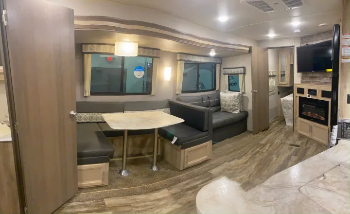 Spacious RV rental interior features a dining booth, sofa, TV, and fireplace, offering a comfortable, modern living space.. Forest River Coachmen Catalina Legacy 2020