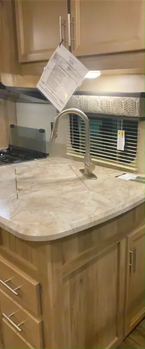 RV rental kitchen: Light counter, gooseneck faucet, stovetop with glass covers, and natural wood cabinets.. Forest River Coachmen Catalina Legacy 2020